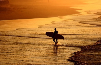 Un surfista sale del agua con su tablón
